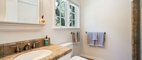 A bathroom with a large sink, a toilet, and a window.