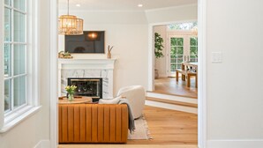Uma sala de estar com lareira, um sofá e um espaço de jantar com mesa e cadeiras.