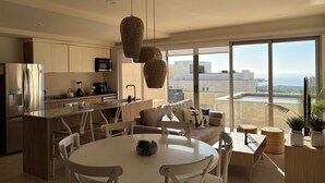 Une cuisine moderne dotée d’un îlot central, d’appareils électroménagers en acier inoxydable et d’une grande fenêtre offrant une vue sur l’océan.