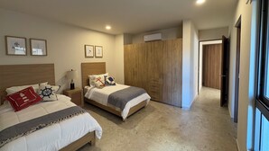 Une chambre d’hôtel avec deux lits, une armoire, une table de chevet avec une lampe et des tableaux encadrés au mur.