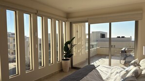Un balcon spacieux avec un lit, une plante en pot et une vue sur le paysage urbain.