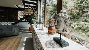Moderni olohuone, jossa on harmaa sohva, sohvapöytä ja Buddha-patsas marmorisella tasolla.