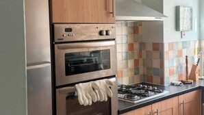 A kitchen with wooden cabinets, a stainless steel refrigerator, a double oven, and a gas stove. - Komegloba Exquisite room (Manchester)