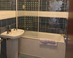 Un baño con lavamanos blanco, bañera y cabina de ducha de vidrio.