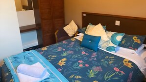 A neatly made bed with floral bedding, a wooden wardrobe, and a mirror on the wall. - OYO Baytree Lodge (Bangor)