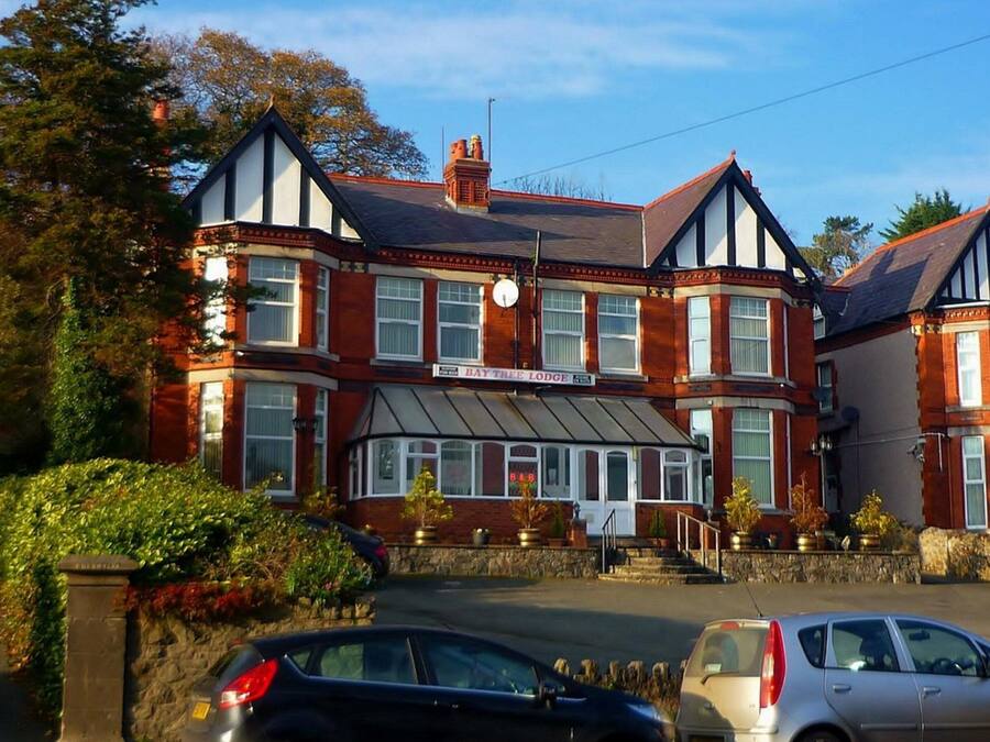 A traditional red brick building with a bay window and a sign reading "Bay Tree Lodge".