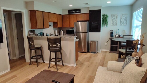 Una cocina moderna con armarios de madera, un refrigerador de acero inoxidable y una barra con dos taburetes.