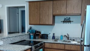 Una cocina moderna con armarios de madera, encimera de granito, horno integrado y refrigerador de acero inoxidable.