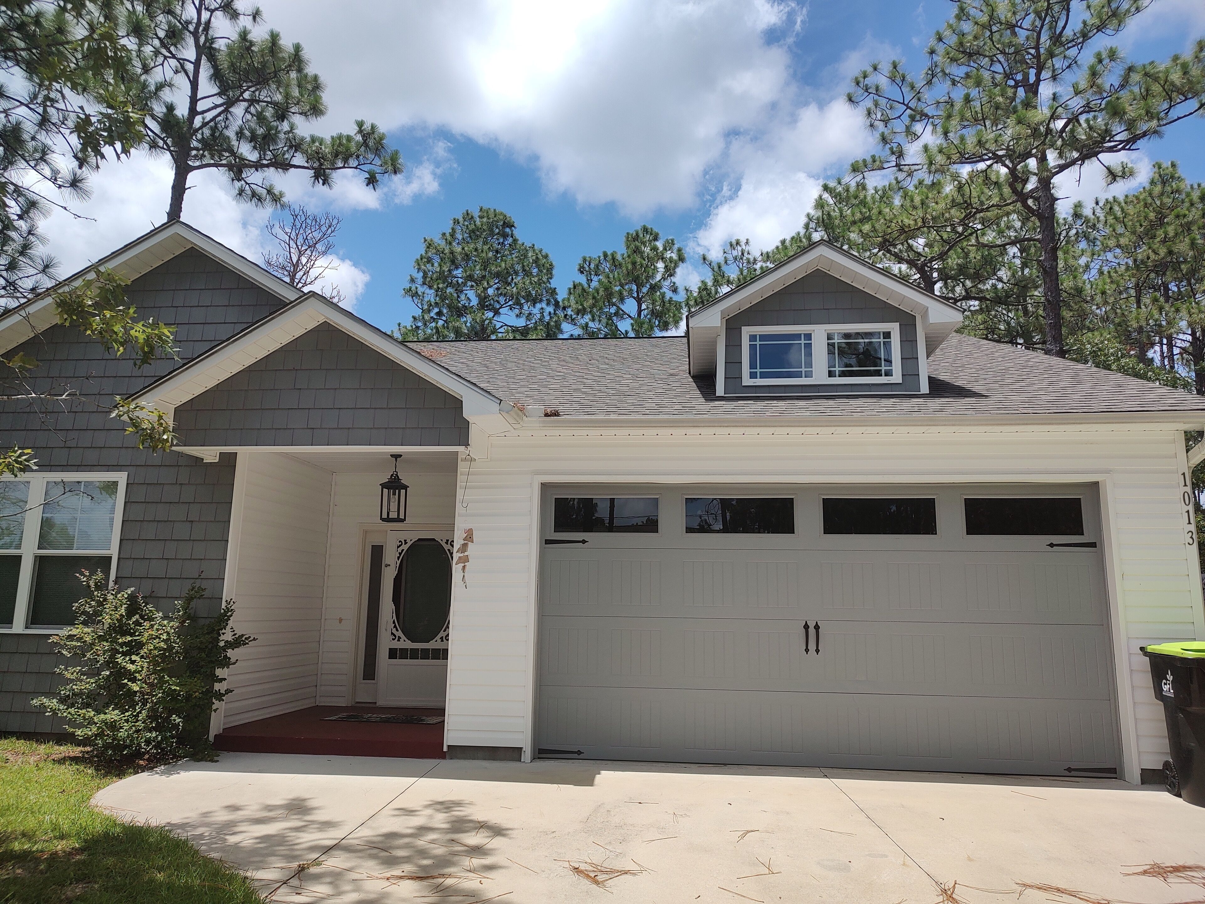 A two-story house with a garage, a front porch, and a small window above the garage.