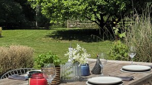 A wooden dining table set outdoors with plates, glasses, and decorative items.