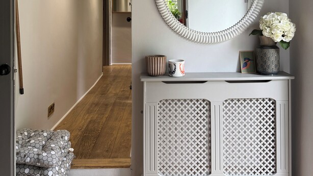 A hallway with a white console table, a round mirror, and a wooden door.