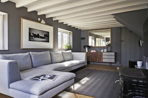 Uma sala de estar moderna com um sofá cinza, um quadro emoldurado, um espelho e um pequeno armário de madeira.
