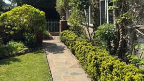A thatched-roof house with a stone pathway leading to a gate.