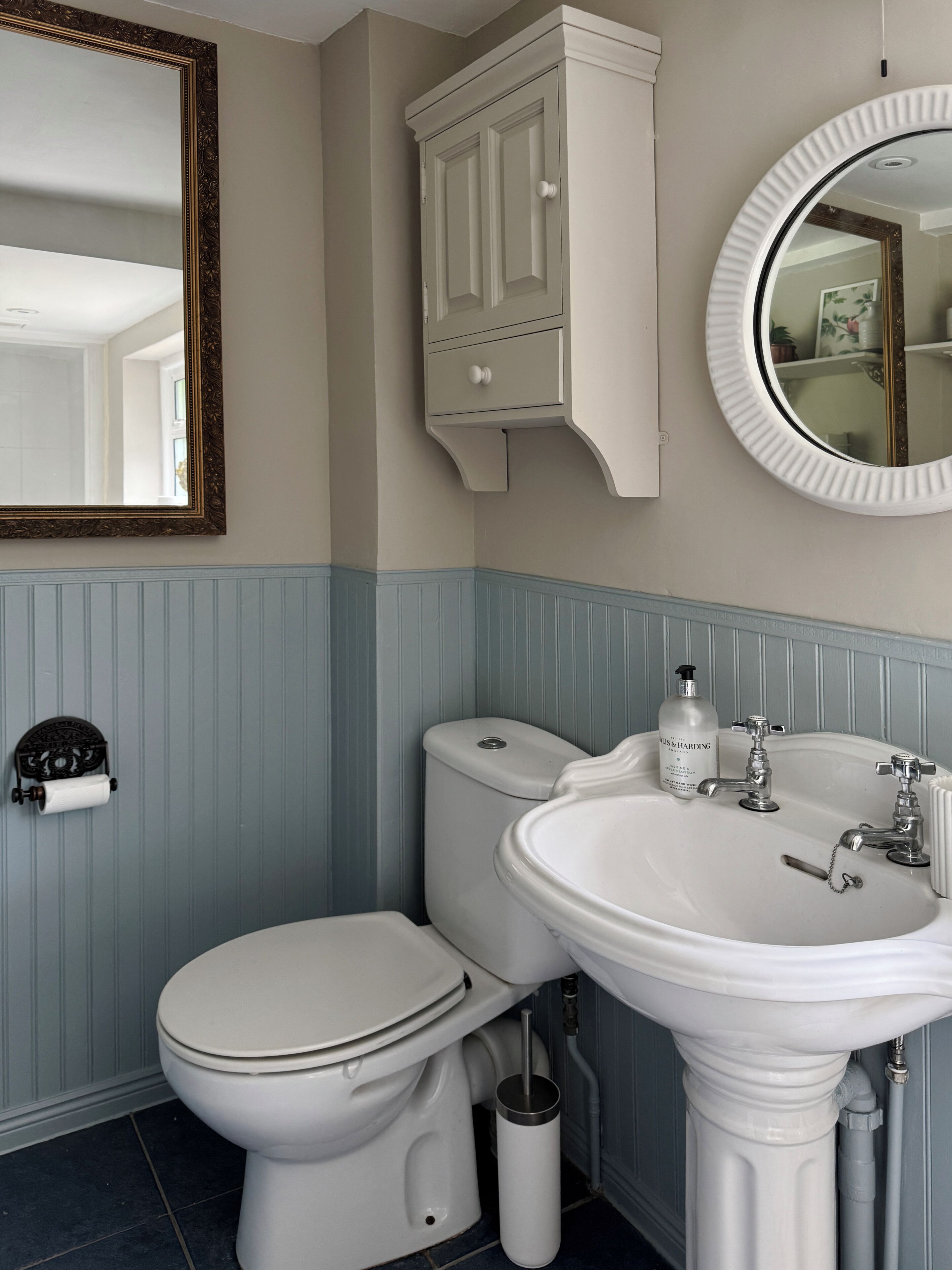 Une salle de bain équipée de toilettes, d’un lavabo, d’un miroir et d’un meuble de rangement.