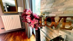 Un interno moderno con una parete in pietra, un termosifone e la parola 'LOVE' decorativa appesa al muro.