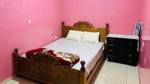 Une pièce comprenant un lit, une commode et un mur muni d’une prise de courant.