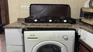 Une cuisine de taille réduite équipée d’un lave-linge, d’une cuisinière et d’un évier.