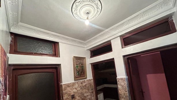 Un couloir avec un mur en marbre, une porte en bois et un tableau encadré accroché au mur.