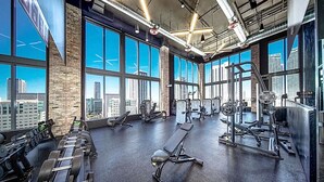 A spacious gym with large windows, various exercise equipment, and a high ceiling. - NEW! Electric Luxury Downtown Bayfront Brickell (Miami)
