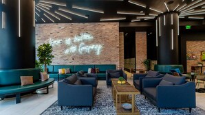 A modern lounge area with dark sofas, a patterned rug, and a neon sign on the wall. - NEW! Electric Luxury Downtown Bayfront Brickell (Miami)