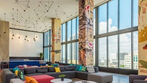 A modern lounge area with a large sectional sofa, two round coffee tables, and a high ceiling with geometric pendant lighting. - NEW! Electric Luxury Downtown Bayfront Brickell (Miami)