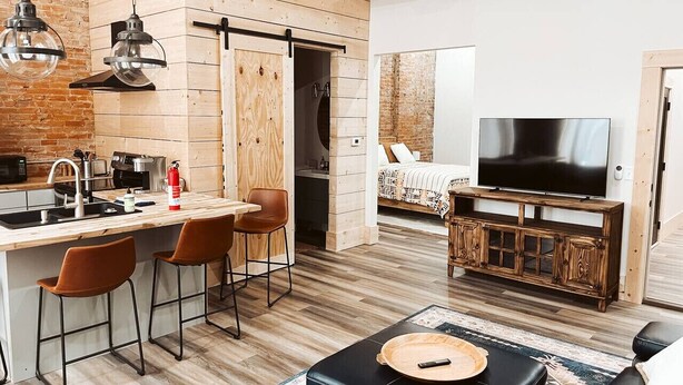 Una cocina moderna con una isla de madera, taburetes de bar y un televisor de pantalla plana.