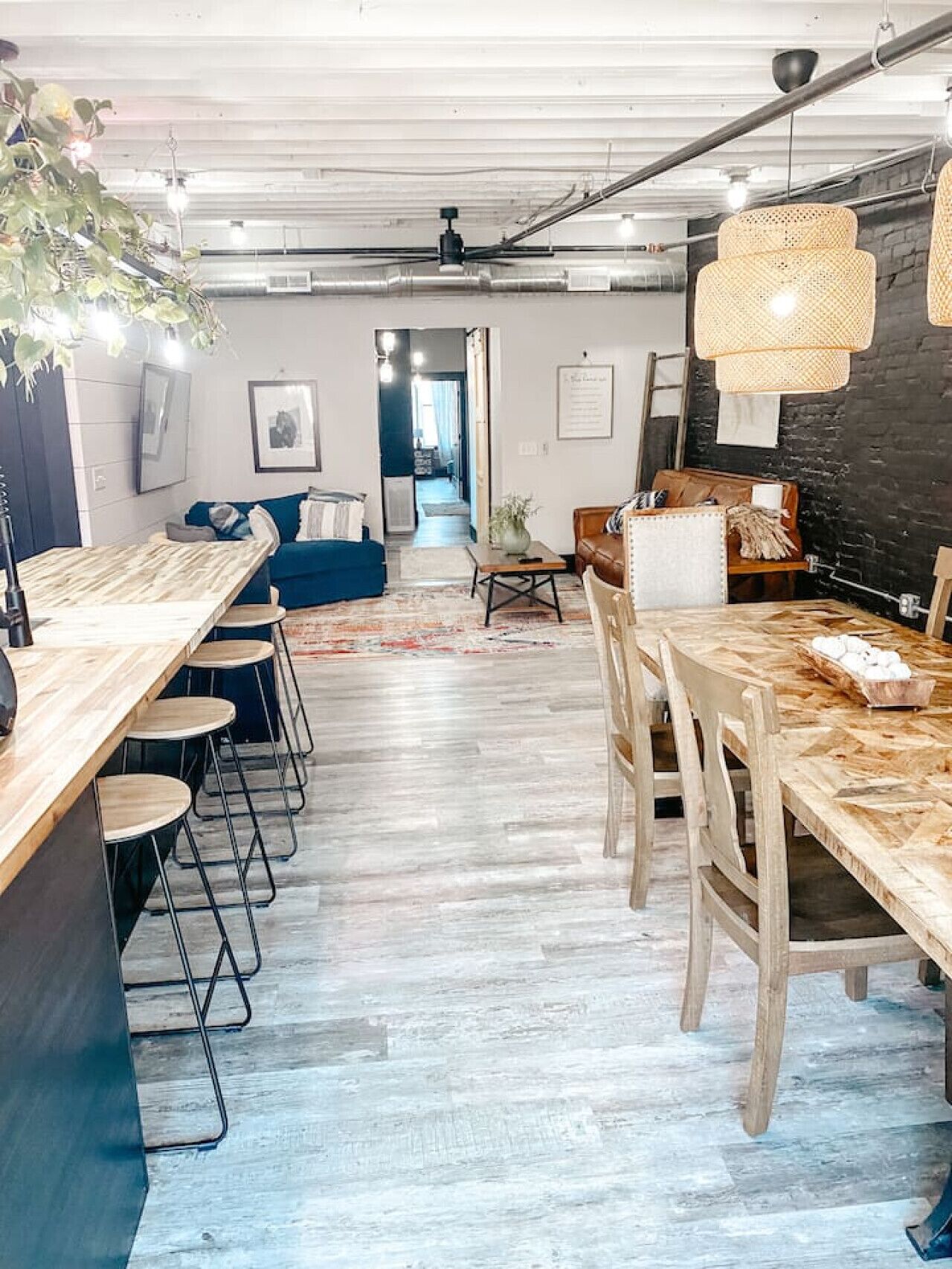 Una cocina moderna con encimera de madera, taburetes de bar y una mesa de comedor con sillas.