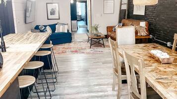 Una cocina moderna con encimera de madera, taburetes de bar y una mesa de comedor con sillas.