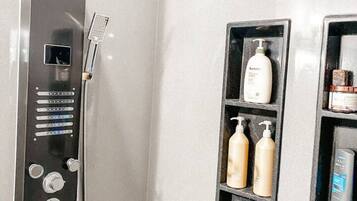 Ein modernes Badezimmer mit Dusche, Bedienfeld und Ablagen für Pflegeprodukte.