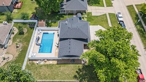 An aerial view of a residential area with a swimming pool, a covered patio, and a large tree. - Urbandale Oasis (Urbandale)