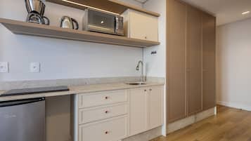 A modern kitchen with a dishwasher, microwave, and coffee maker on a shelf, a sink, and wooden cabinets.