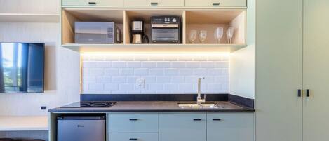 A modern kitchen with a built-in oven, coffee maker, and wine glasses on display.