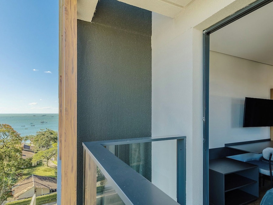 Un balcón con vista al mar y un interior moderno con televisor de pantalla plana.