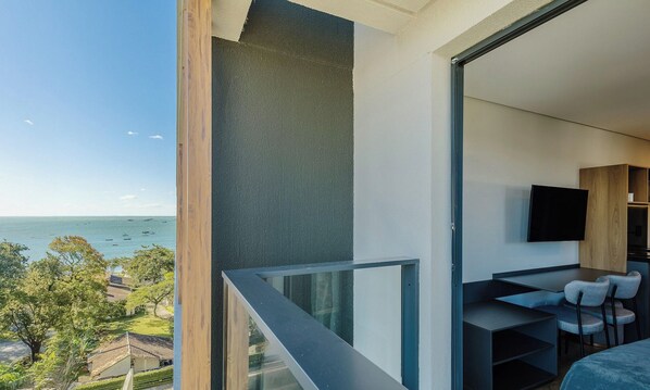 A balcony with a view of the sea and a modern interior with a flat-screen TV. - Studios With Side Sea View at Penha Spot PSO - L (Penha)