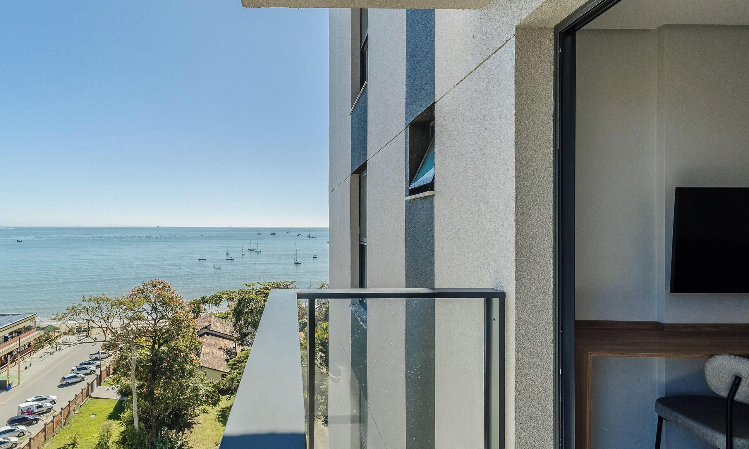 Ein Balkon mit Meerblick und Booten, ein an der Wand befestigter Fernseher und ein Stuhl.