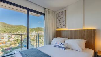 A hotel room with a large bed, a view of a cityscape, and a wooden headboard.