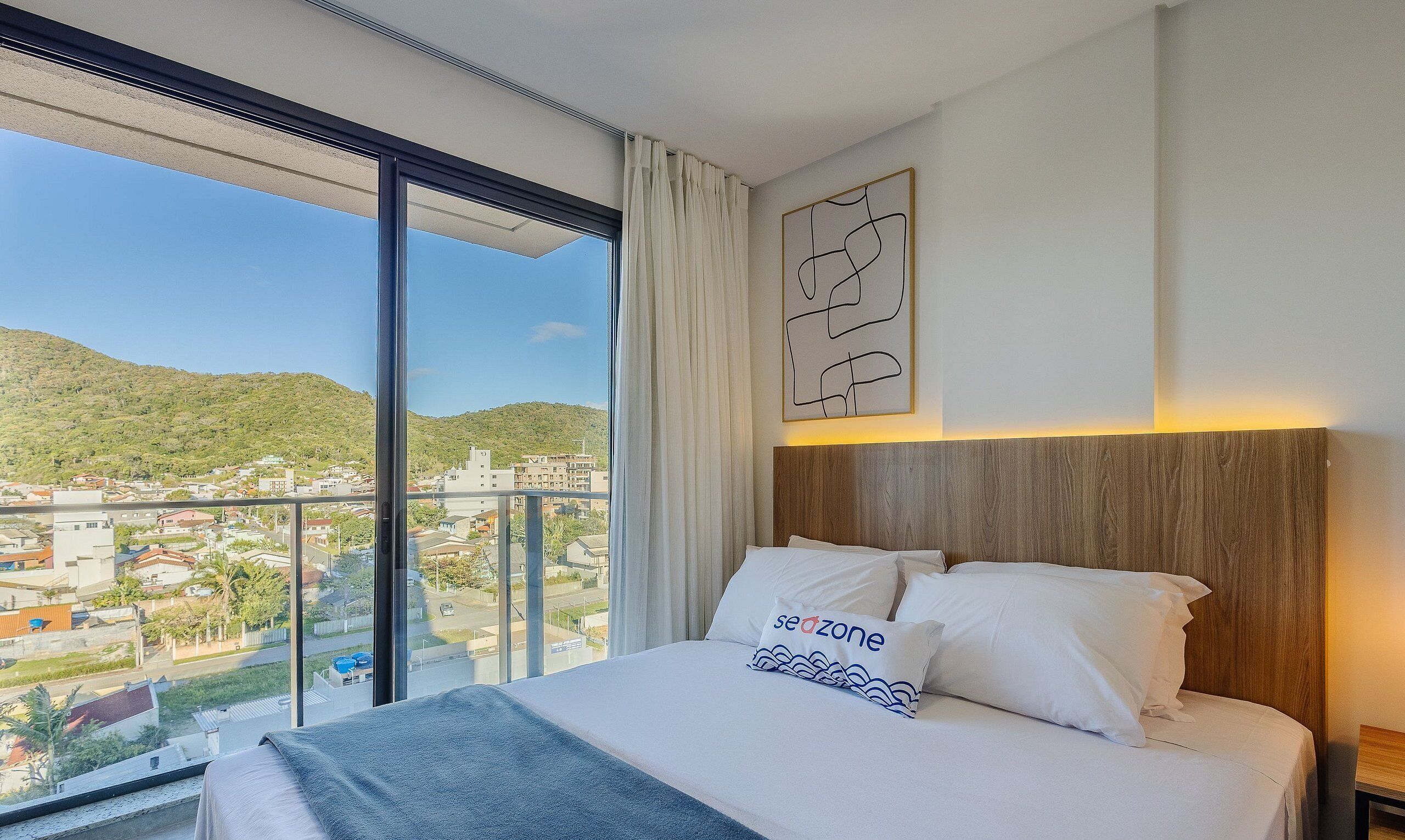 Una habitación de hotel con una cama grande, vistas a un paisaje urbano y un cabecero de madera.