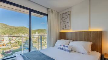 Una habitación de hotel con una cama grande, vistas a un paisaje urbano y un cabecero de madera.