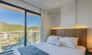 A hotel room with a large bed, a view of a cityscape, and a wooden headboard. - Studios With Side Sea View at Penha Spot PSO - L (Penha)