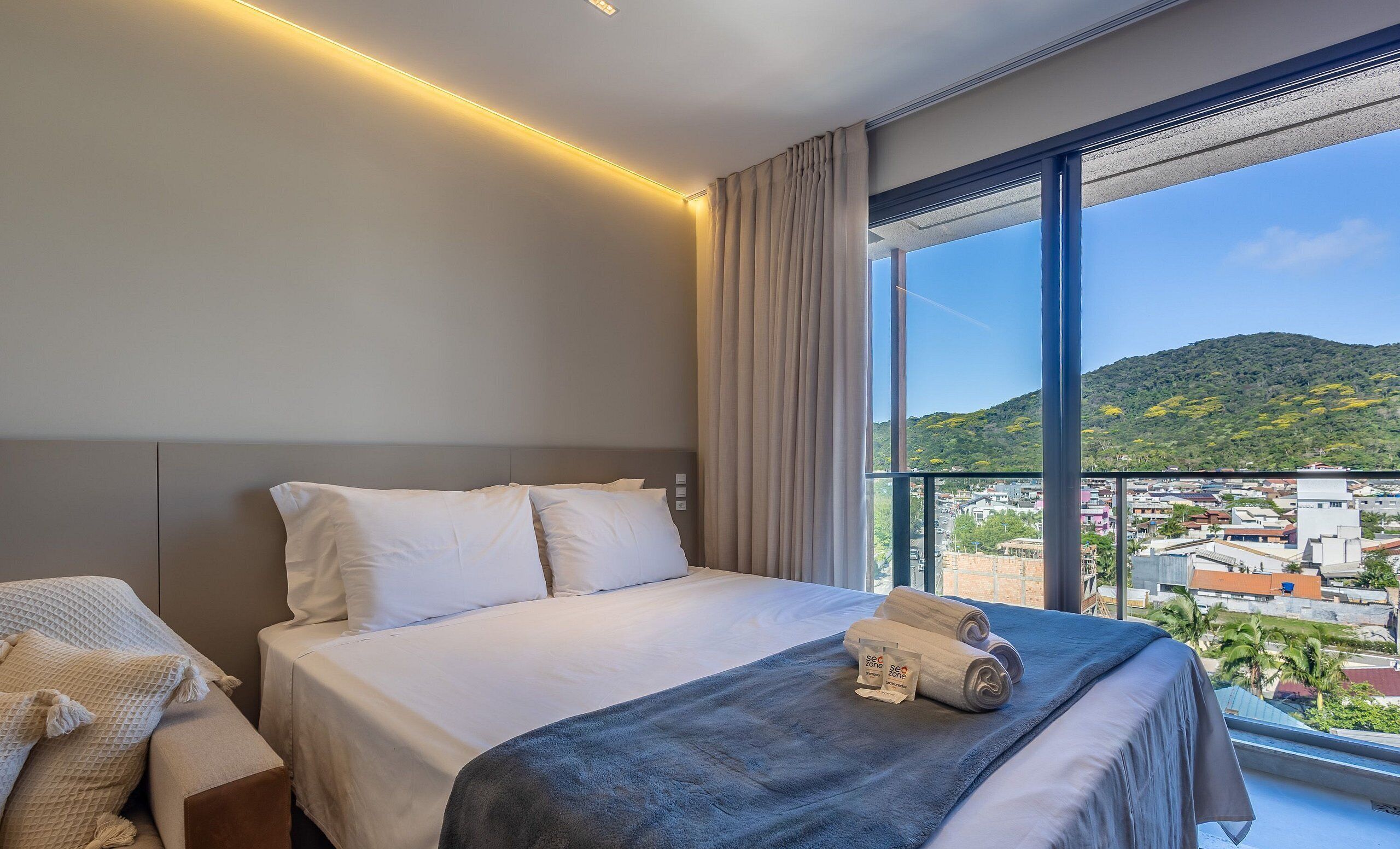 Habitación de hotel con cama, vistas a la ciudad y balcón.