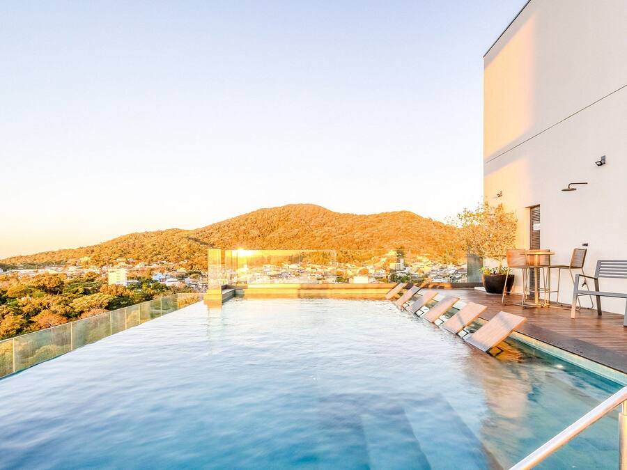 Piscina con sillas de descanso, vista a la montaña y un edificio con un letrero.