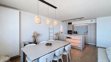 Une cuisine moderne dotée d’un îlot central, de luminaires suspendus et d’un coin repas avec une table et des chaises.