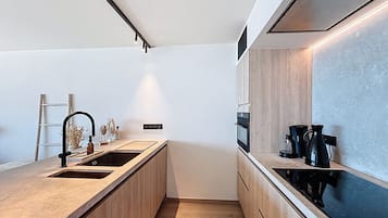 Une cuisine moderne dotée d’un îlot central, d’appareils électroménagers intégrés et d’un design minimaliste.