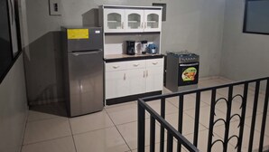 A kitchen with a refrigerator, a coffee maker, and a small stove. - All inclusive apartment (San Salvador)