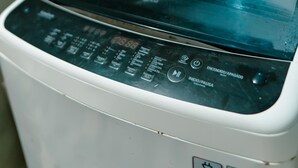 A front view of a washing machine with a digital display, control panel, and safety labels. - All inclusive apartment (San Salvador)