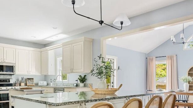 Una cocina moderna con una isla central, sillas de madera y una zona de comedor con mesa y sillas.