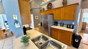 A kitchen with wooden cabinets, stainless steel appliances, a sink, and a coffee maker.