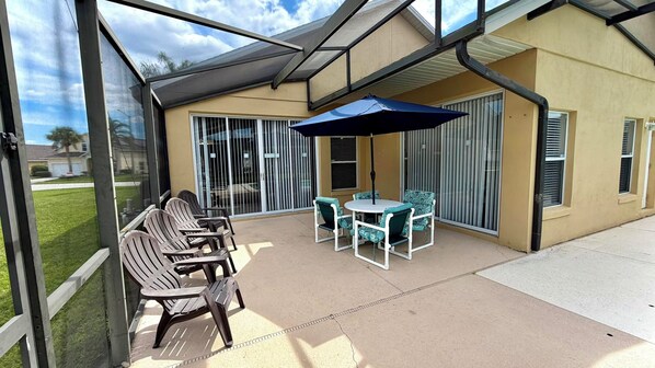 A covered patio with outdoor furniture and a glass door leading to a garage.