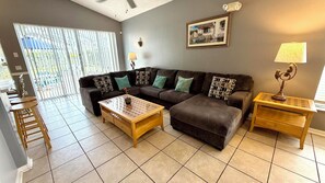A living room with a sofa, two coffee tables, a lamp, and a picture on the wall.