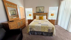 A bedroom with a bed, a dresser, a mirror, two bedside tables, and a window with blinds.